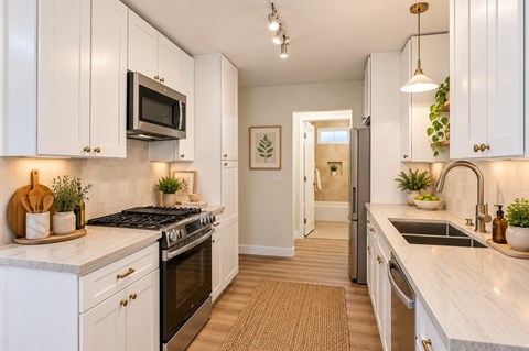 Staged Ocean View Townhomes kitchen with white cabinets and a black stove top oven.