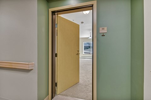 an open door leading into a room with a hallway with green walls