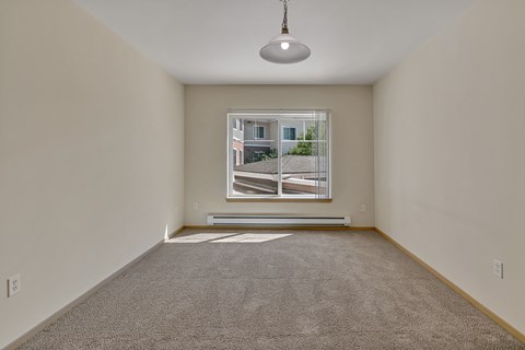 an empty living room with a large window and carpet