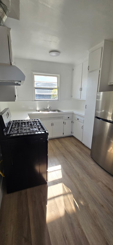A kitchen with a stainless steel refrigerator and wooden floors.