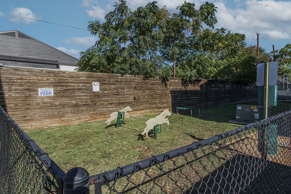 A park with a fence and a sign on a wooden wall.