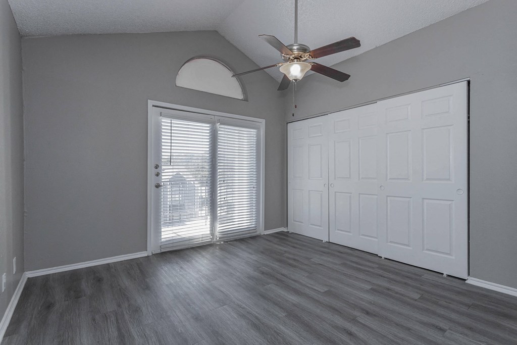 A room with a ceiling fan and a sliding glass door.