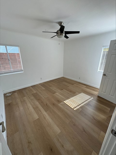an empty room with wooden floors and a ceiling fan