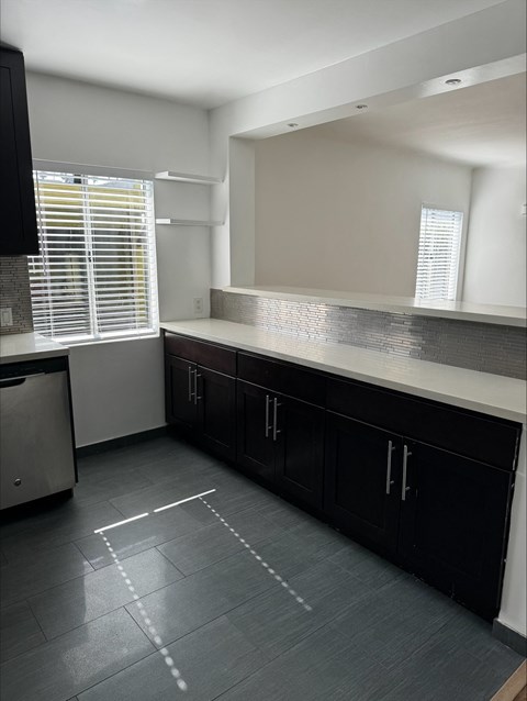 an empty kitchen with black cabinets and a large mirror