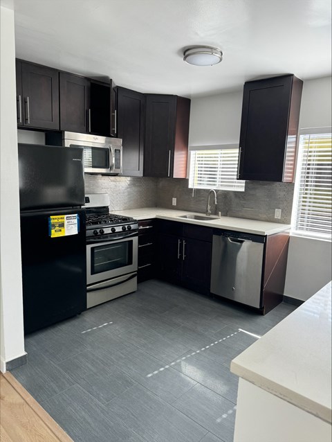 an empty kitchen with black cabinets and stainless steel appliances