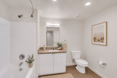 A white bathroom with a toilet, sink, and mirror.