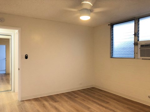 an empty living room with a ceiling fan and a window