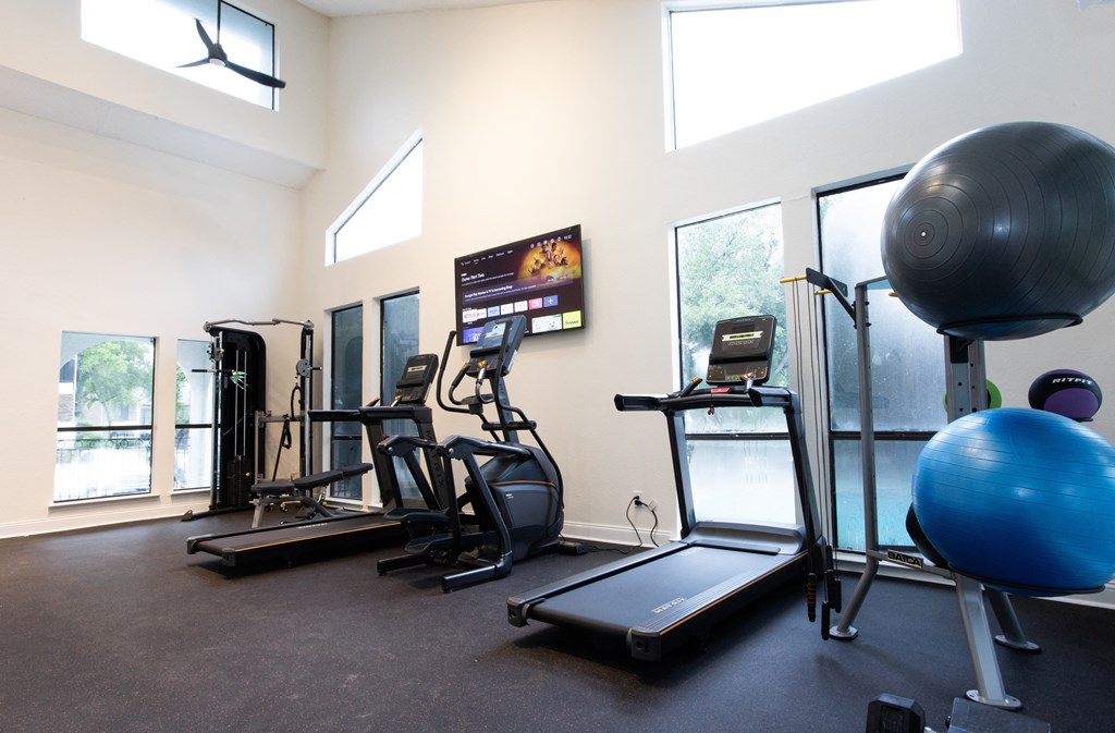a gym with various exercise equipment in a room with windows