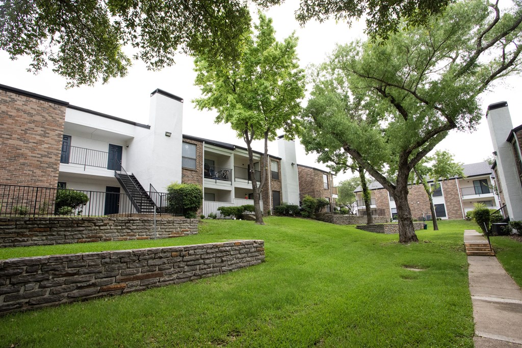exterior view of apartments with a green lawn and trees