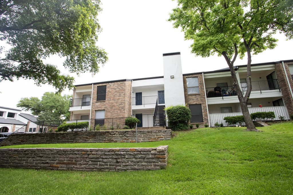 the outlook of an apartment building with green grass and trees