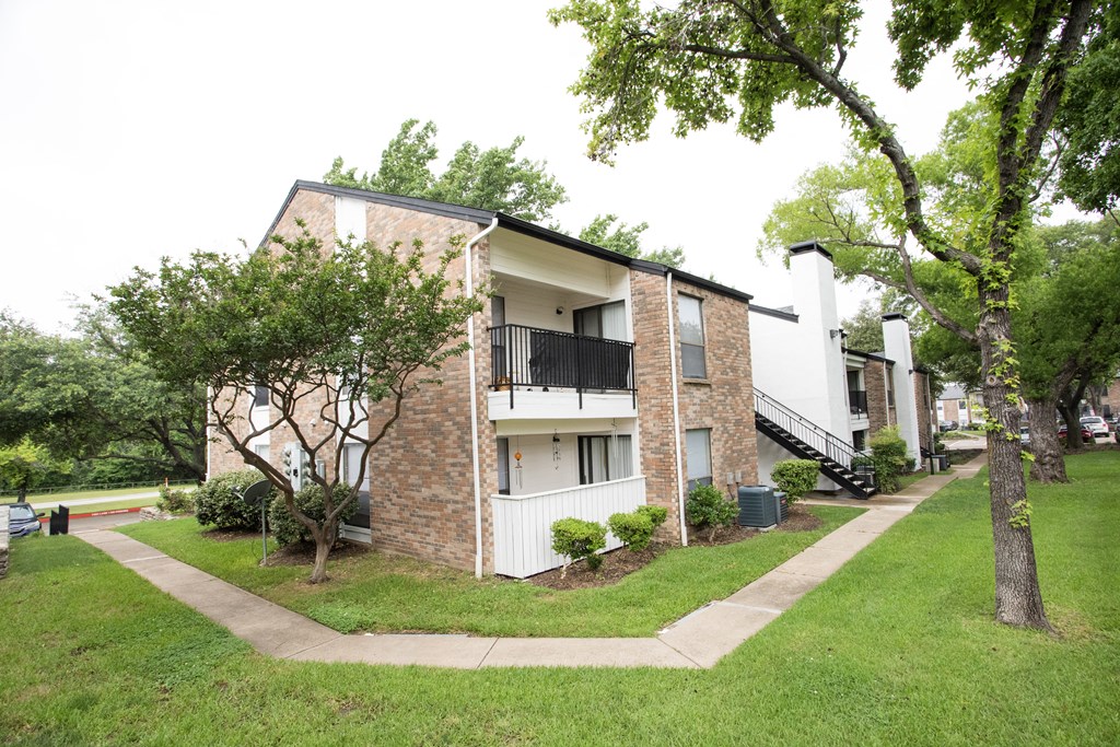 the outlook of an apartment building with a lawn and trees