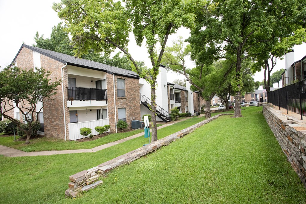 the apartments are located next to a green lawn and trees