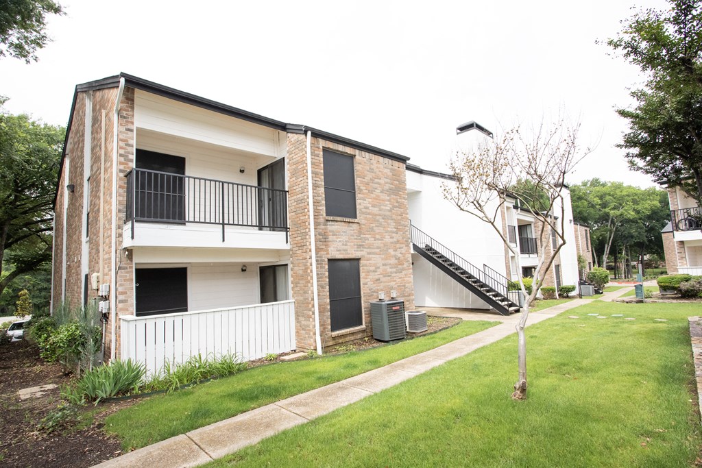 the exterior of an apartment building with a lawn and a staircase