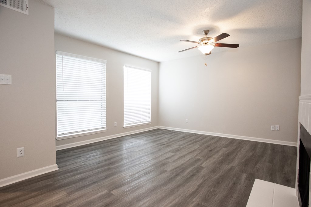 an empty living room with wood floors and a ceiling fan