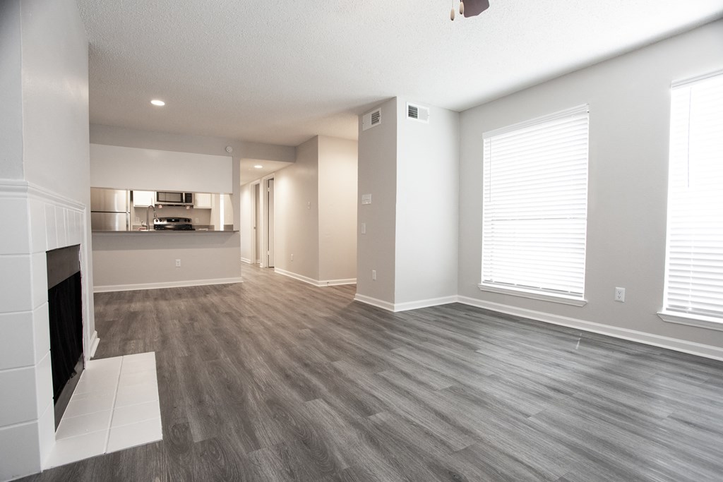 an empty living room with a fireplace and a kitchen