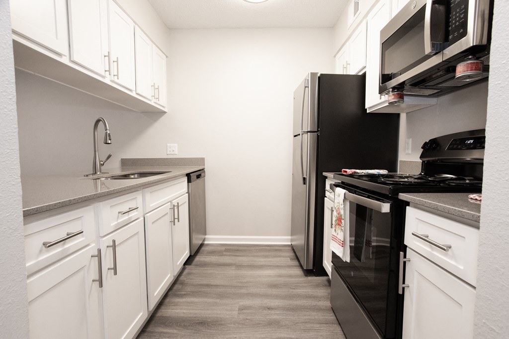 a kitchen with white cabinets and a black stove and refrigerator