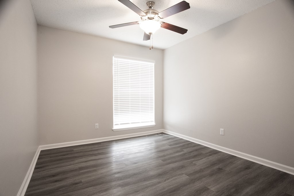 an empty living room with a ceiling fan and a window