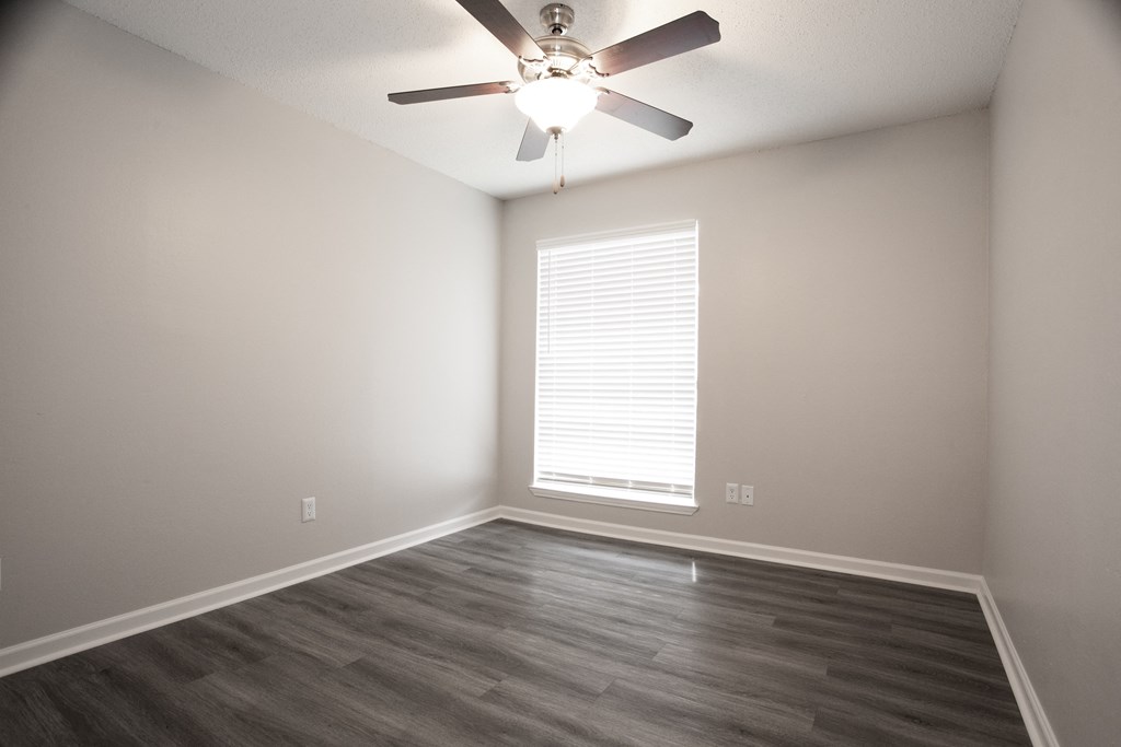 an empty living room with a ceiling fan and a window