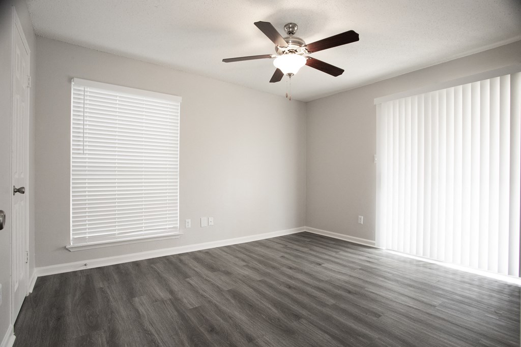 an empty living room with wood floors and a ceiling fan