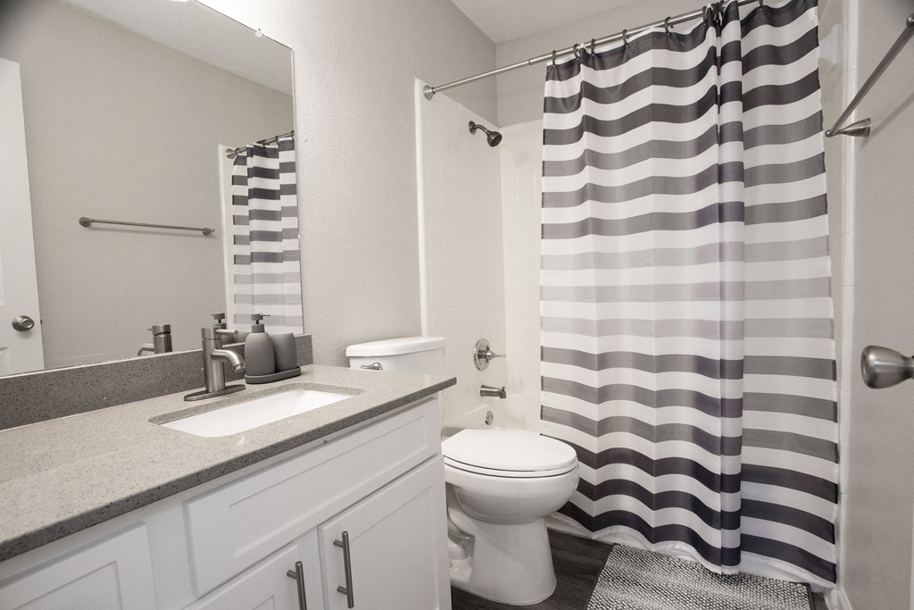 a white bathroom with a black and white shower curtain