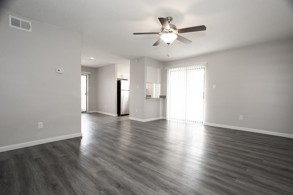 an empty living room with wood floors and a ceiling fan