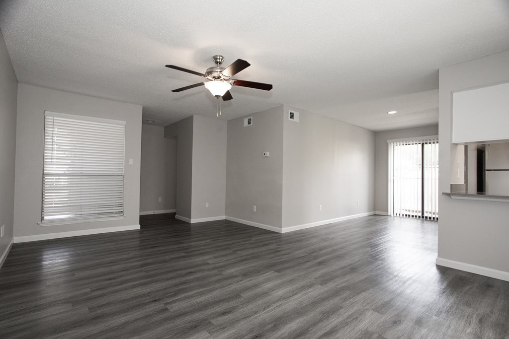 an empty living room with a ceiling fan and a window