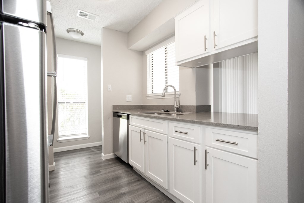 an empty kitchen with white cabinets and a stainless steel refrigerator