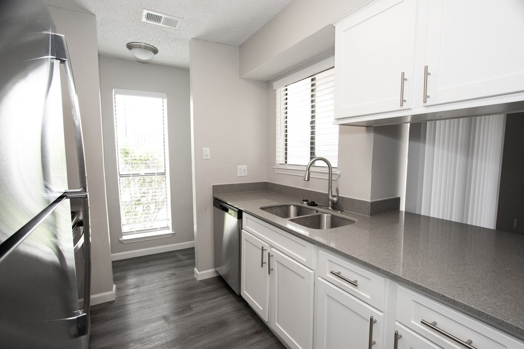 an empty kitchen with white cabinets and a stainless steel sink