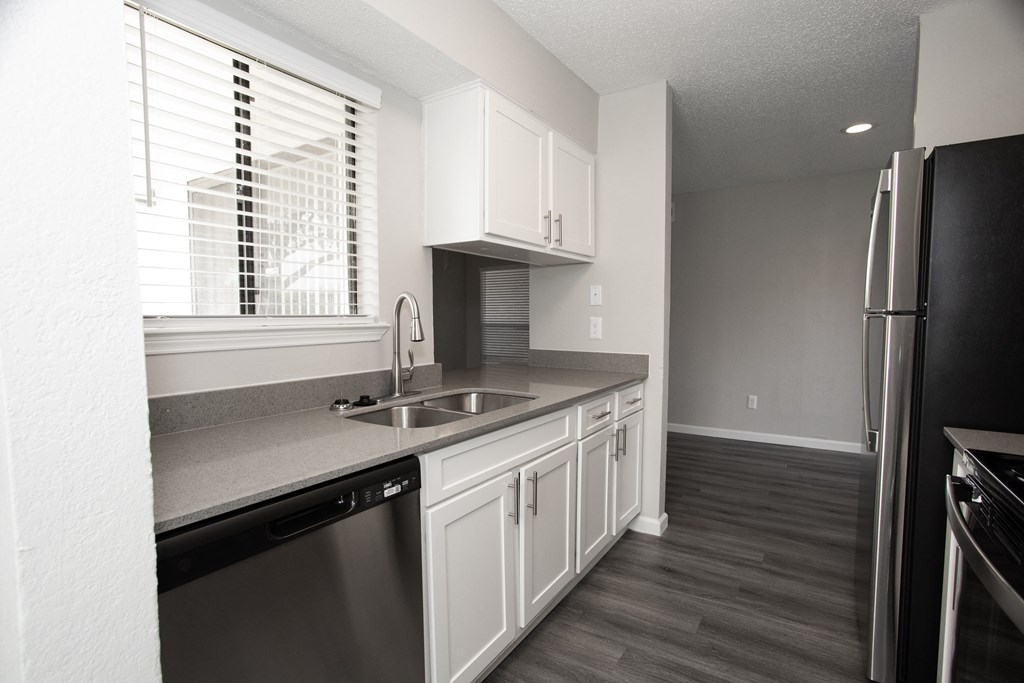 a kitchen with white cabinets and a sink and a window