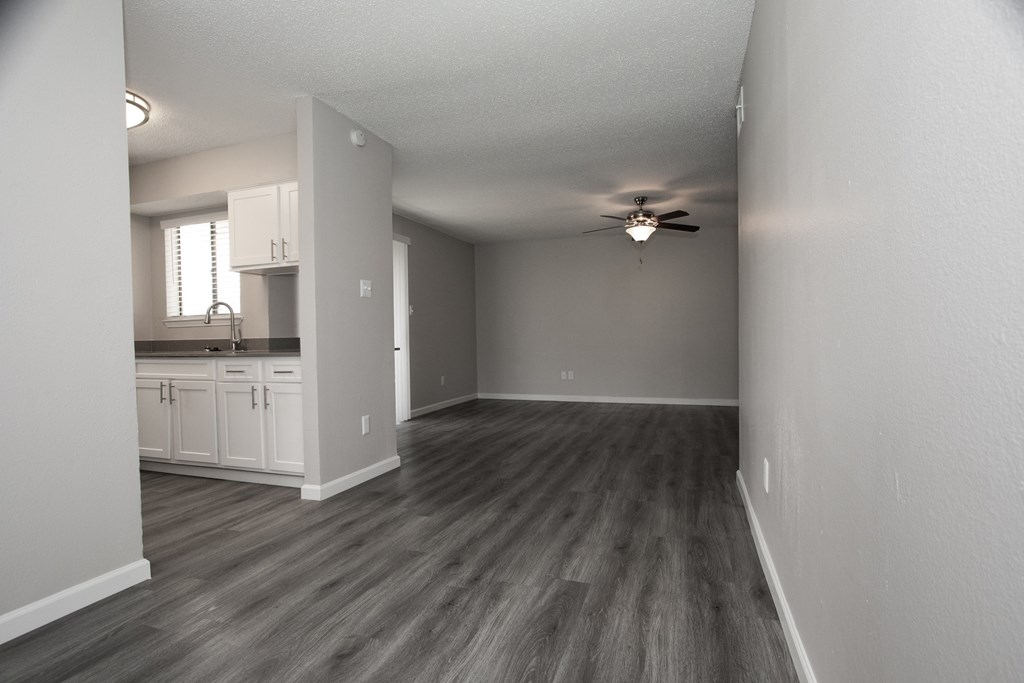 an empty living room and kitchen with a ceiling fan