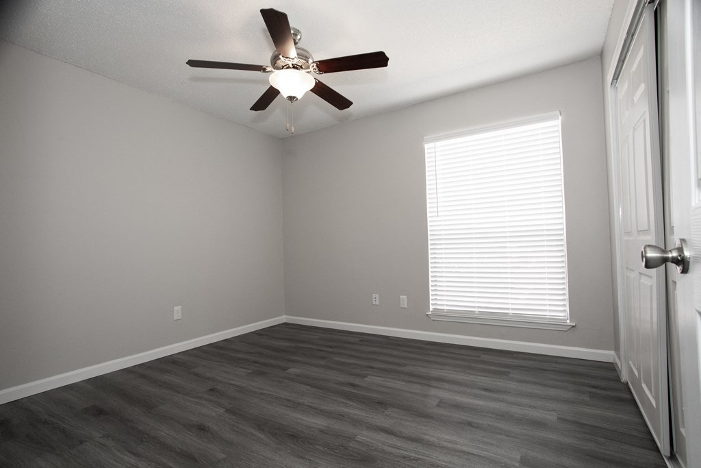 an empty room with a ceiling fan and a window