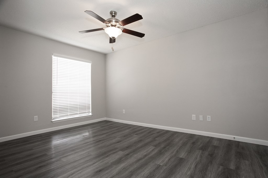 an empty living room with a ceiling fan and a window