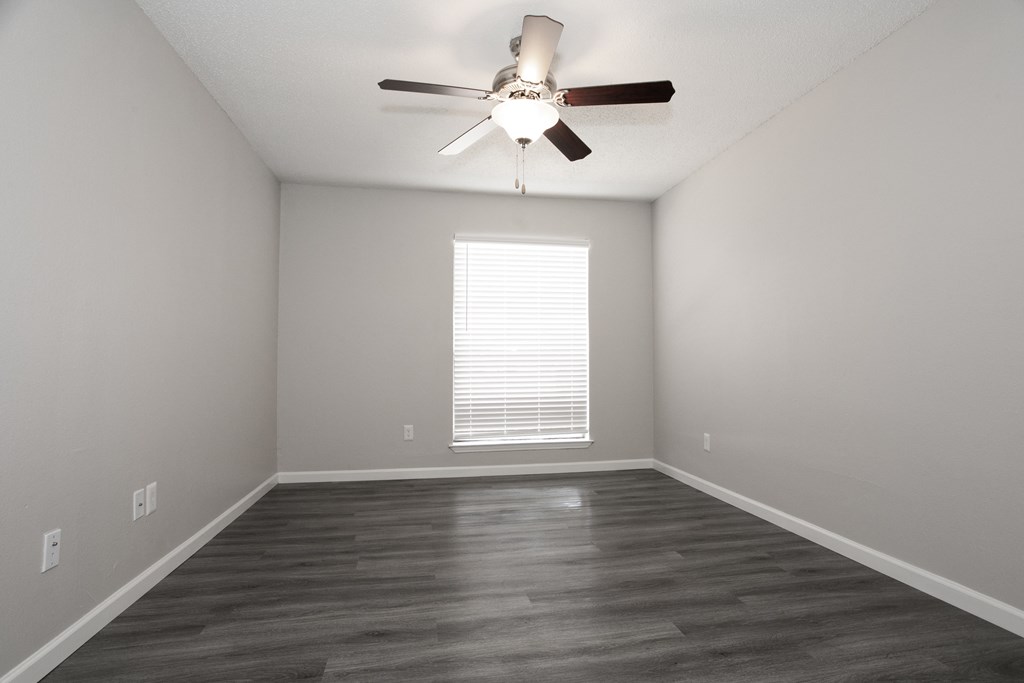 an empty living room with a ceiling fan and a window
