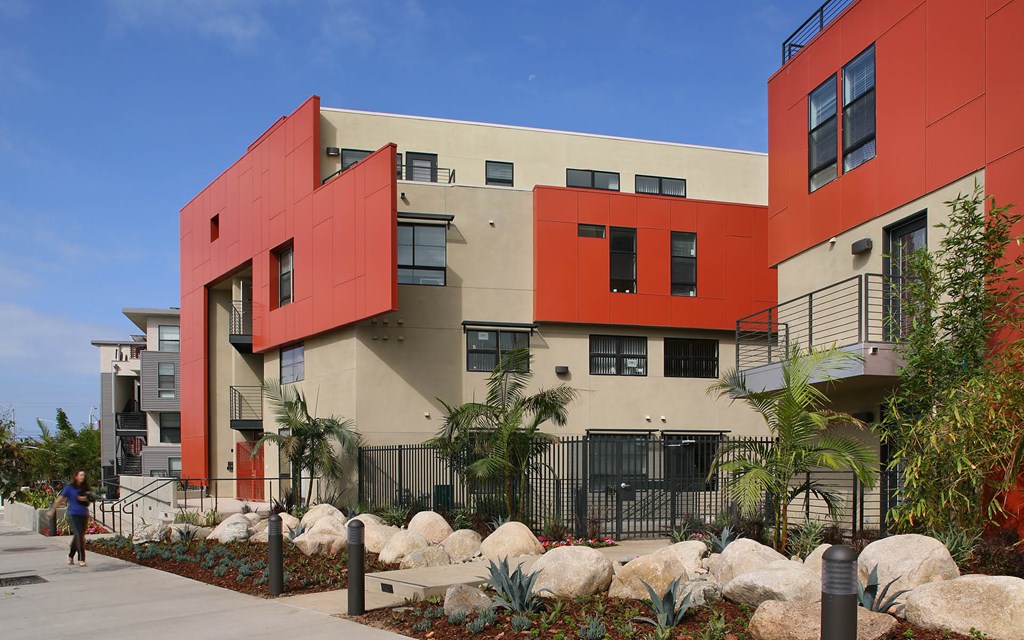 A red and beige building with a person walking in front of it.