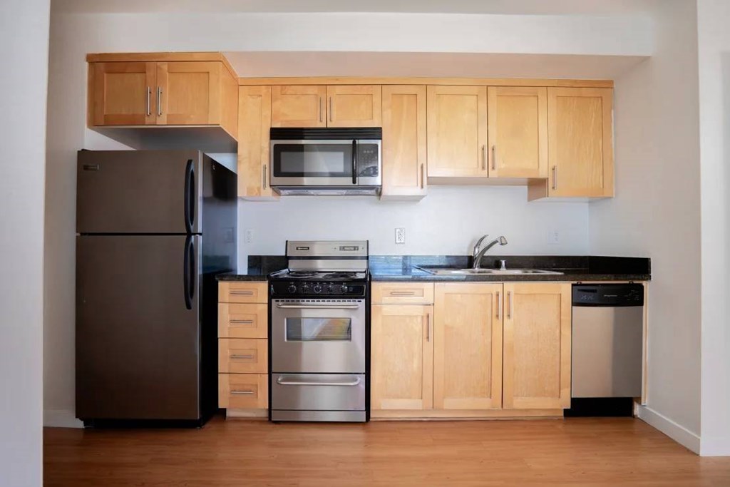 A kitchen with wooden cabinets and a black countertop.