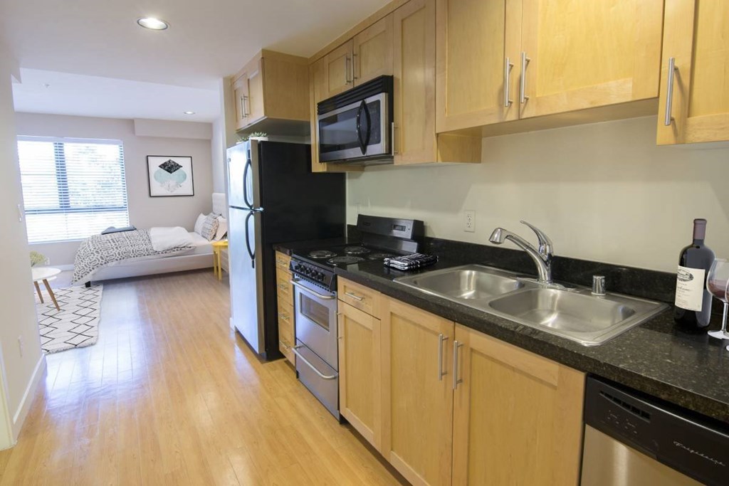 A kitchen with black appliances and wooden cabinets.