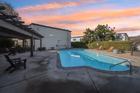A swimming pool in a backyard with a sunset sky.