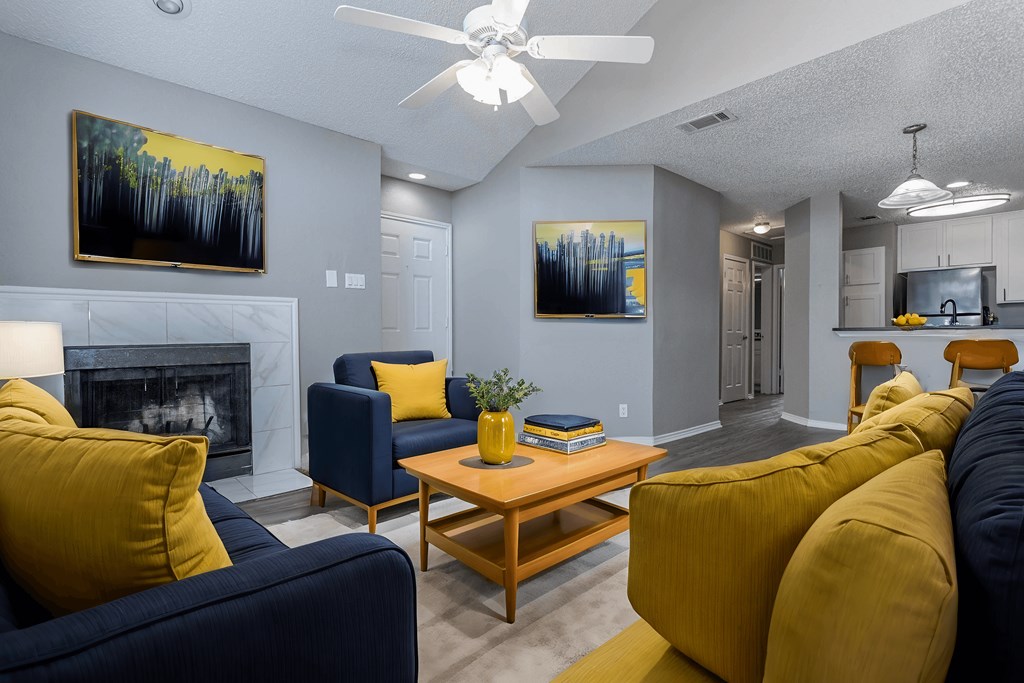 A living room with a fireplace, two couches, a coffee table, and two paintings on the wall.