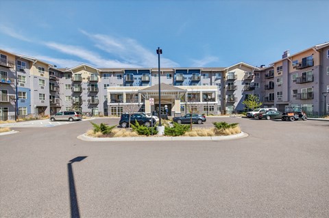 A parking lot in front of apartment buildings on a sunny day.