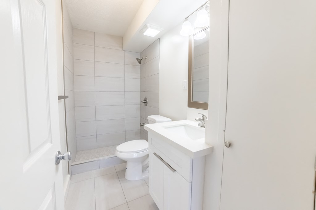 A white bathroom with a toilet, sink, and mirror.