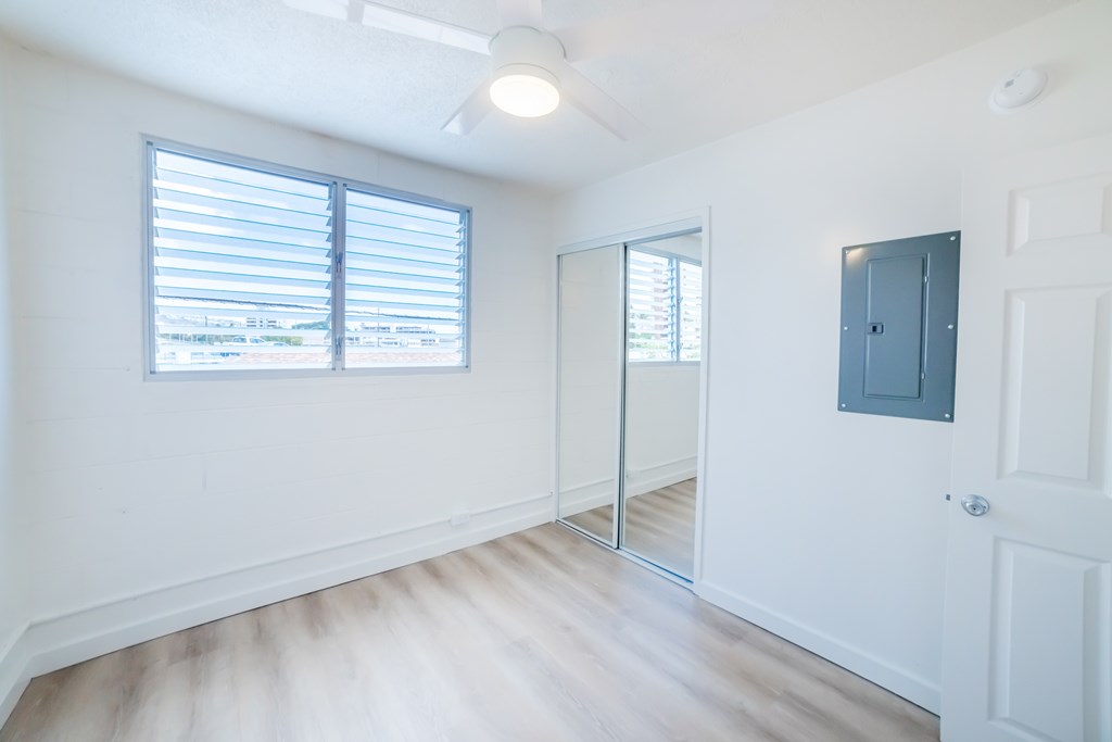 A room with a white door, a mirror, and a window with blinds.