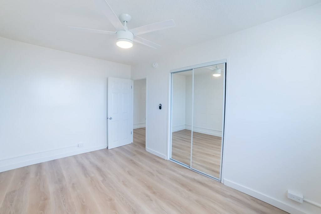 A room with a white ceiling, wooden floor, and a glass door.