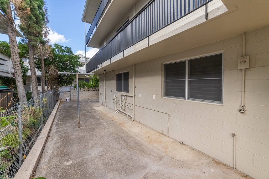 A concrete patio is surrounded by a building and trees.