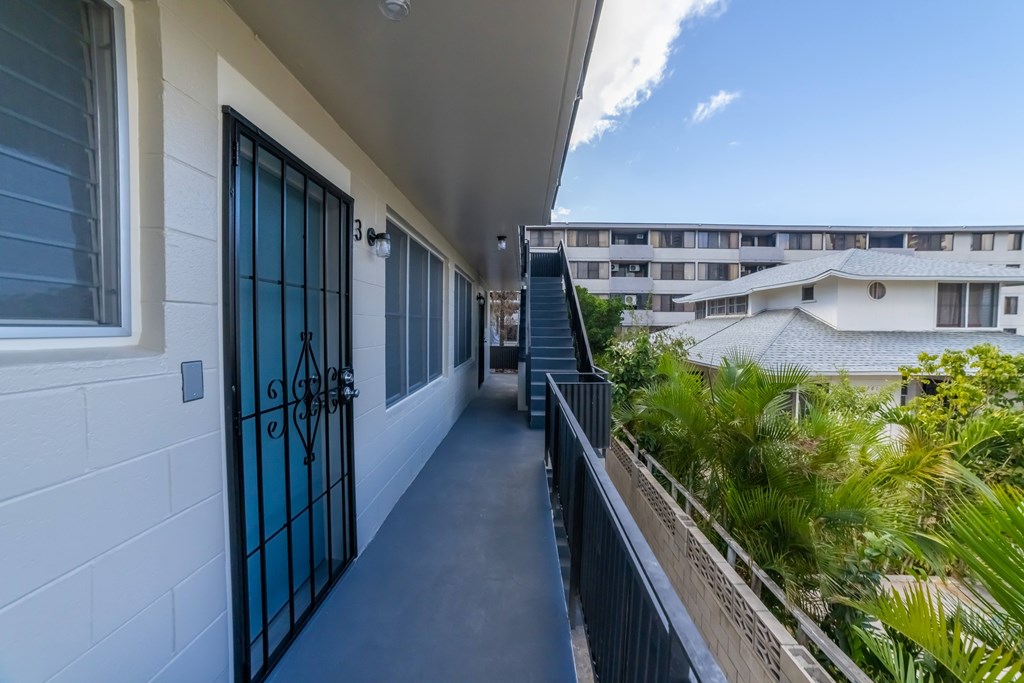 A balcony with a black railing and a view of a building across the way.