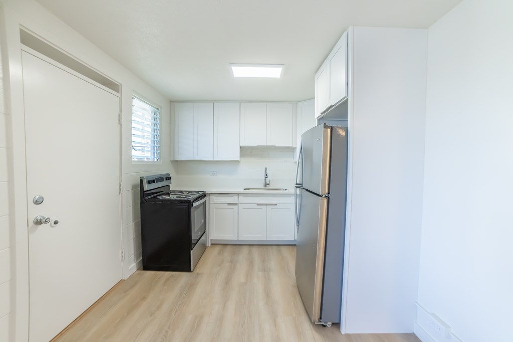 A kitchen with white cabinets and a black fridge.