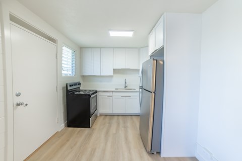 A kitchen with white cabinets and a black fridge.
