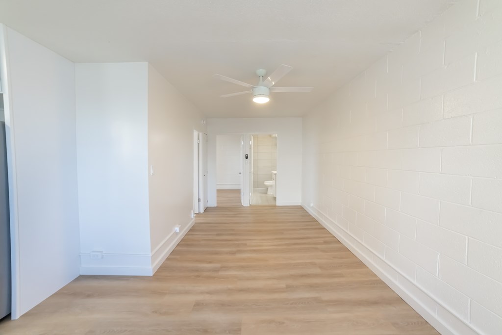 A long, empty hallway with wooden floors and white walls.