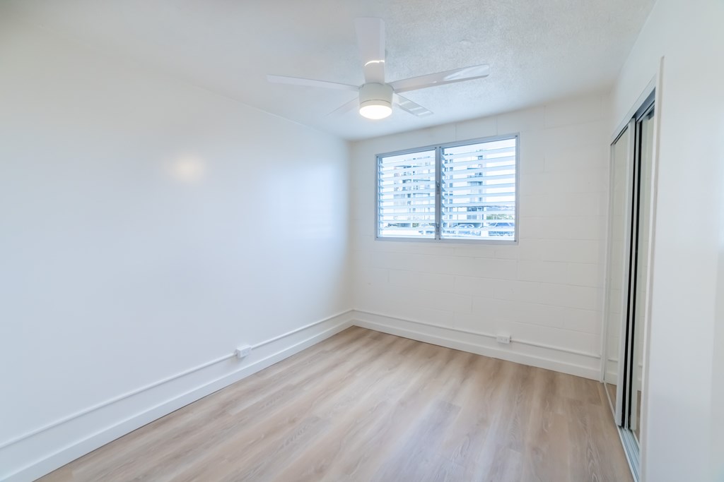 A room with a ceiling fan and a window with blinds.