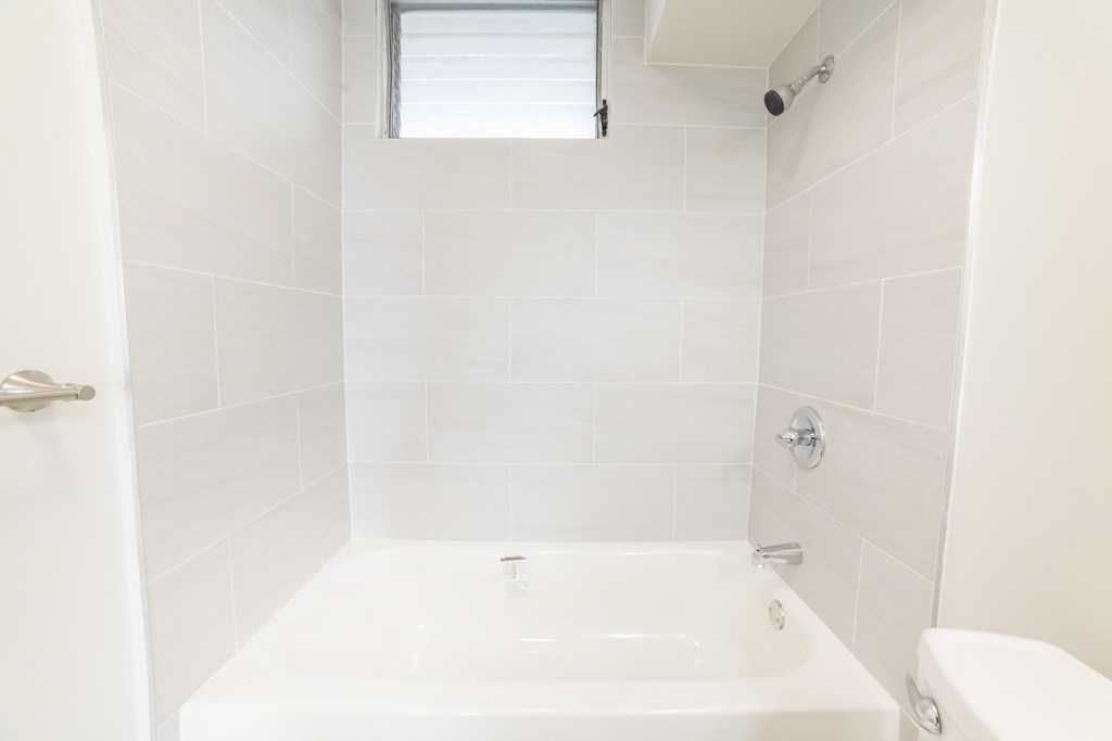 a white bathroom with a tub and a window