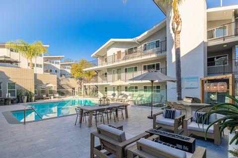 a swimming pool with a table and chairs in front of a building